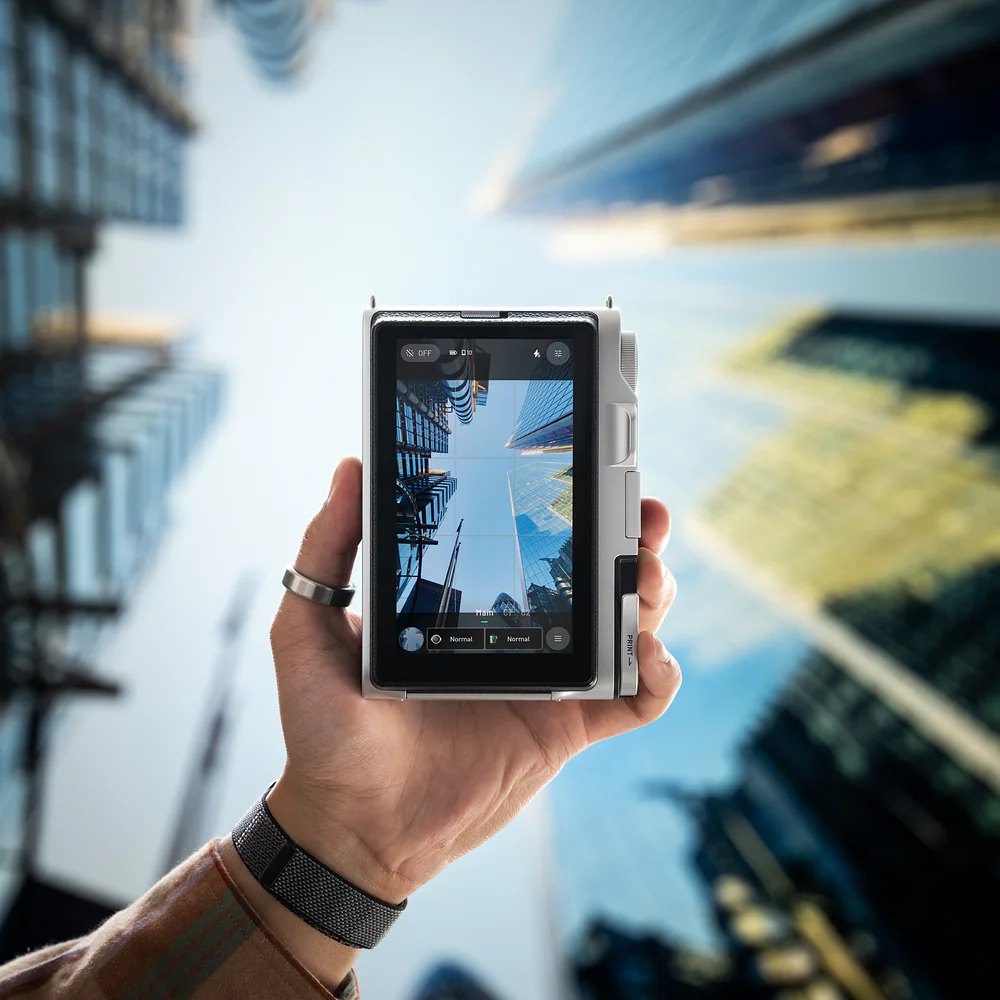 instax mini Evo 2 w dłoni z ekranem dotykowym