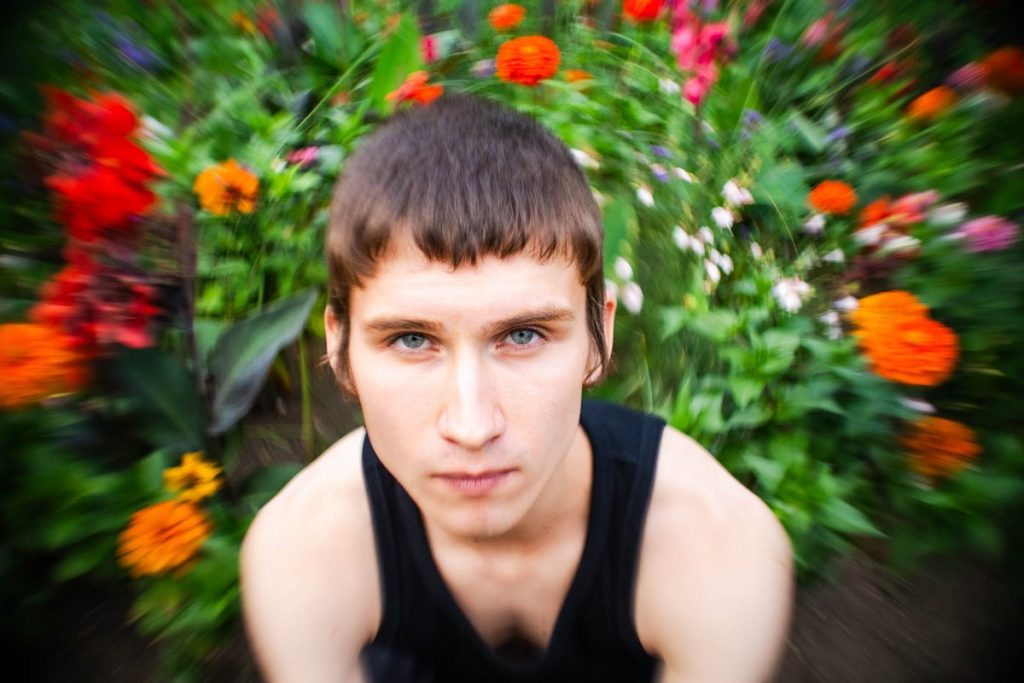 Portret wykonany obiektywem Lomography Petzval Métamorphose 35 mm z wirującym tłem kwiatów