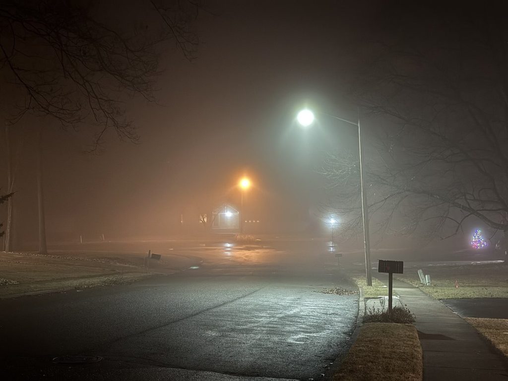 Pusta ulica nocą we mgle, latarnie o różnych barwach światła
