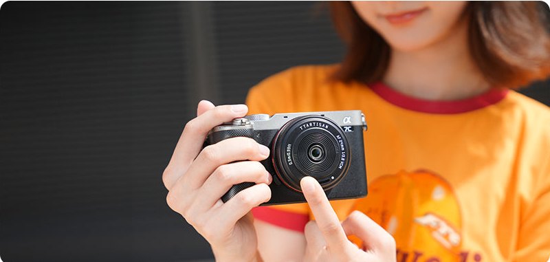 TTartisan AF 24mm F3.8 mini na aparacie w dłoniach fotografki